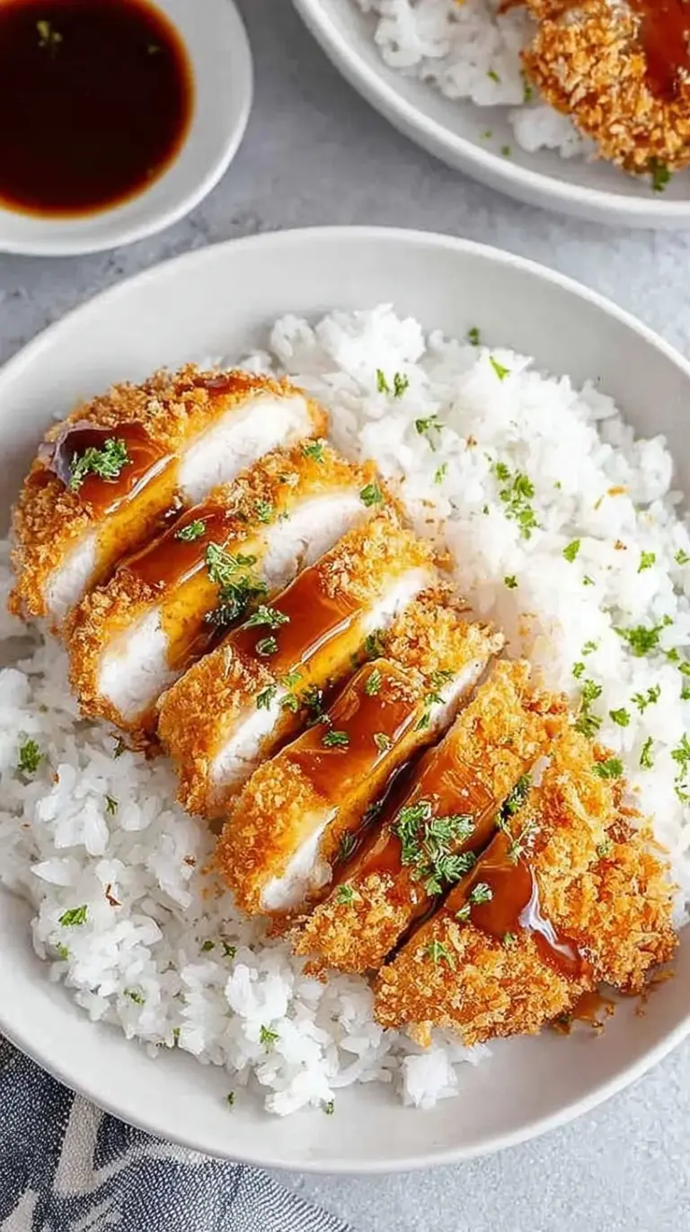 Golden brown sliced Air Fryer Chicken Katsu served on a white plate with cabbage.