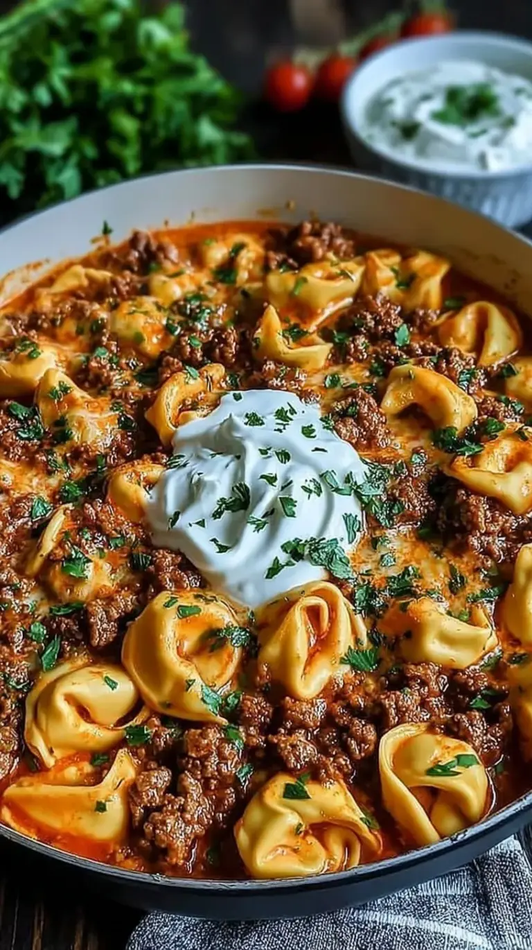A skillet of cheesy beef enchilada tortellini topped with melted cheese and fresh cilantro