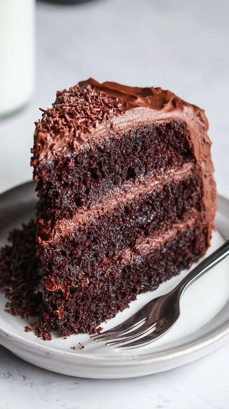 A moist slice of dark chocolate cake made with applesauce on a white plate.