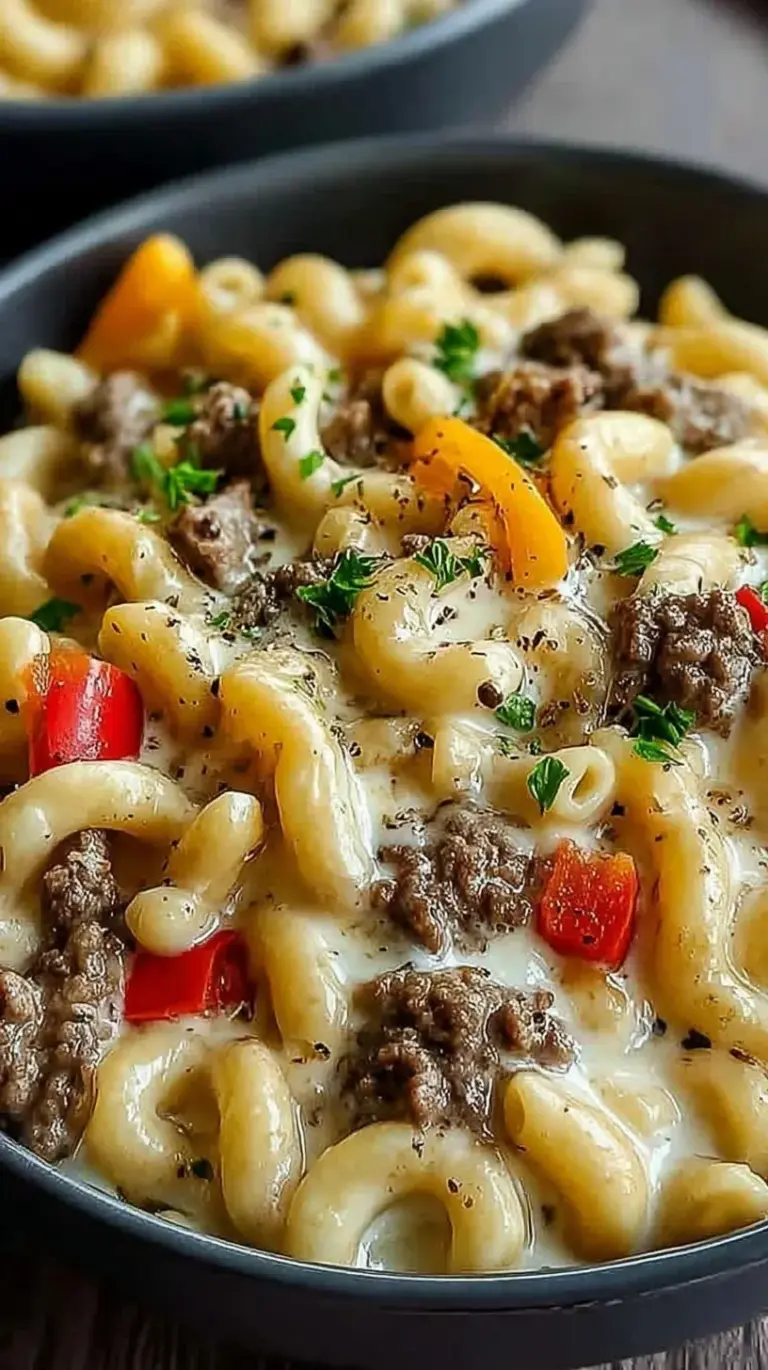 Creamy Philly cheesesteak mac and cheese with sliced steak and green peppers in a bowl