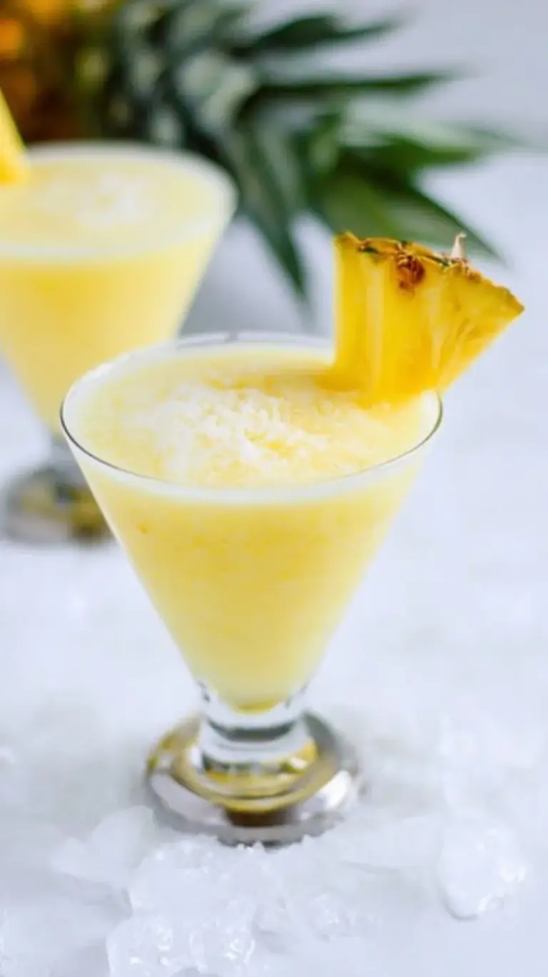 A frosty Skinny Piña Colada in a glass with a pineapple wedge garnish